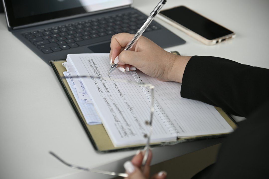 Person recording details in notebook beside laptop, illustrative image for SEBI SCORES complaint evidence and case tracking