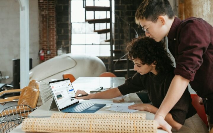 Small business team laptop के साथ AI-enabled workflow पर काम करते हुए